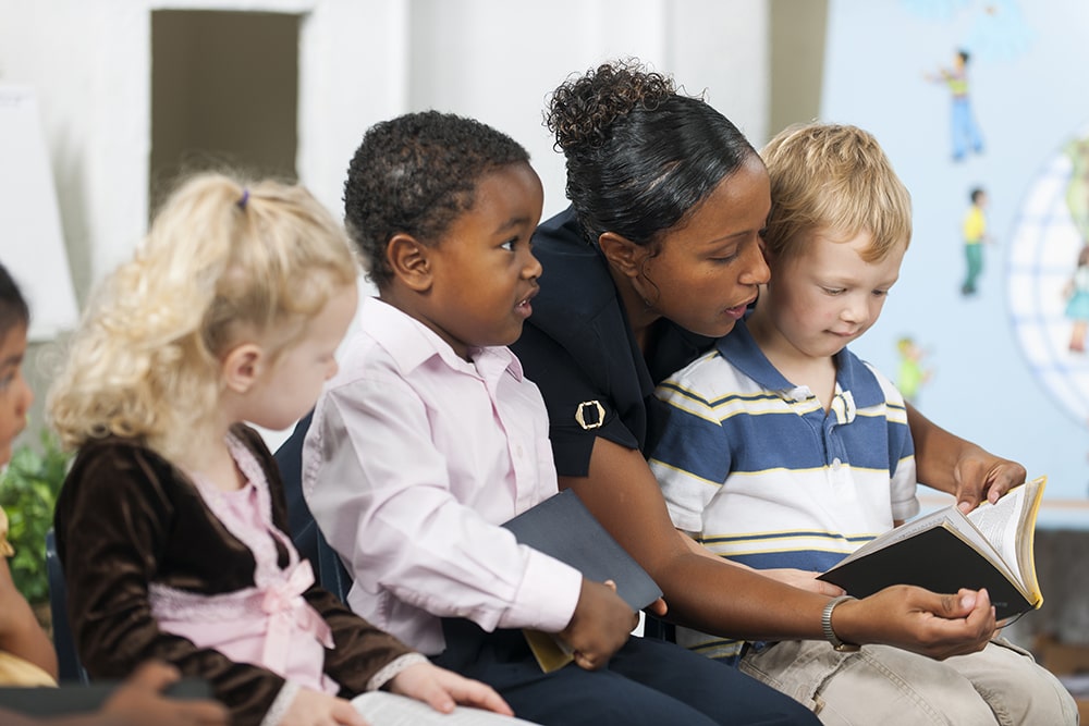 Students and adult looking through Bible